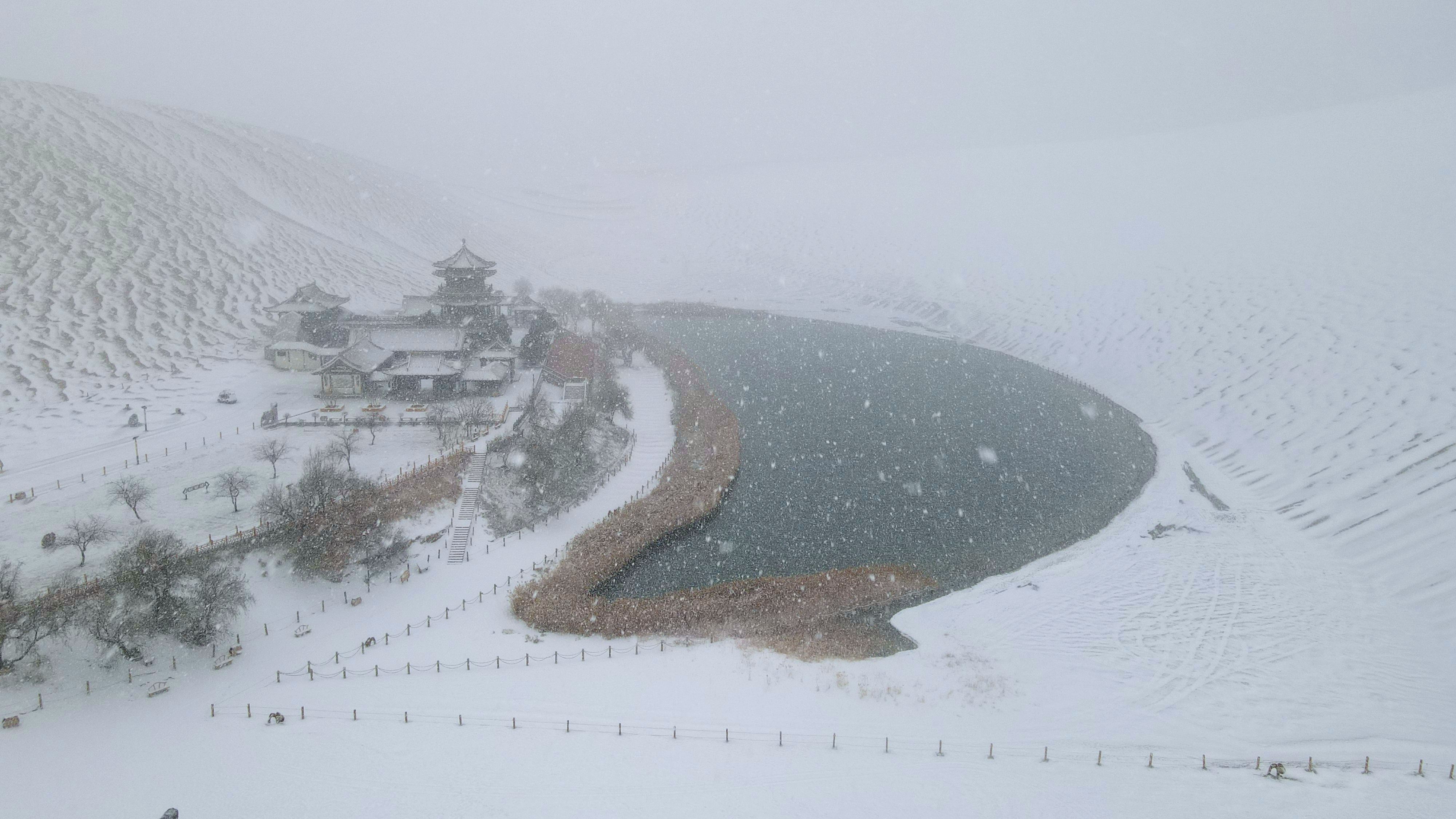 2022年11月27日拍攝的甘肅省敦煌市鳴沙山月牙泉景區雪景（無人機照片）。張曉亮攝