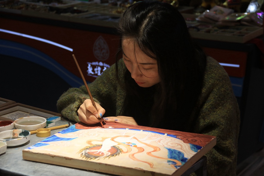 泥板畫藝人在敦煌夜市繪制泥板畫作品。張曉亮攝