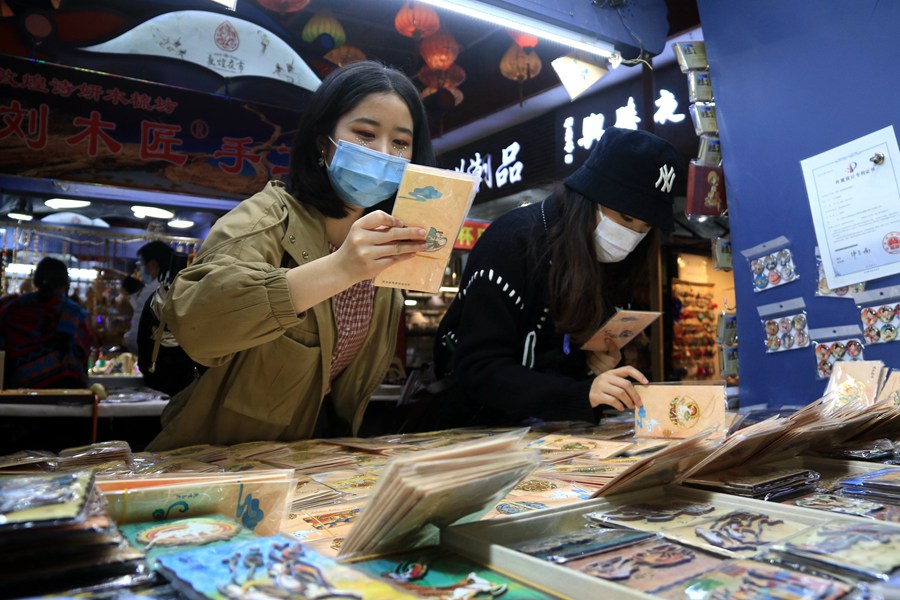 游客在敦煌夜市欣賞選購敦煌文化元素書簽。張曉亮攝