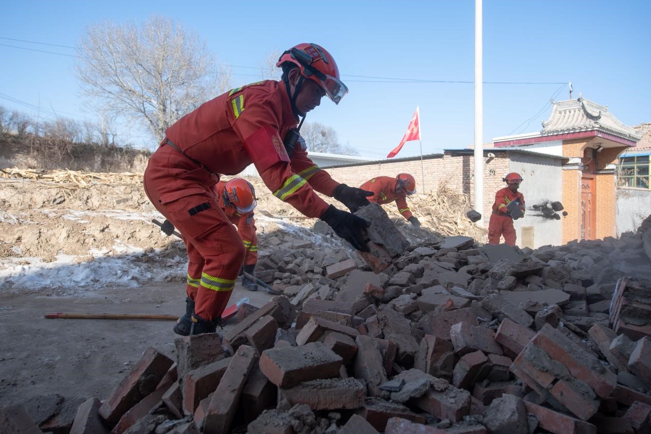 12月21日，在積石山縣石塬鎮石塬村，消防救援人員正在清理村中道路。人民網記者 翁奇羽攝