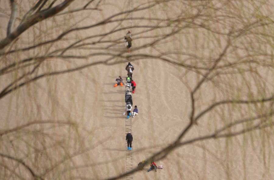 3月24日，游客在甘肅省敦煌市鳴沙山月牙泉景區游覽。張曉亮攝