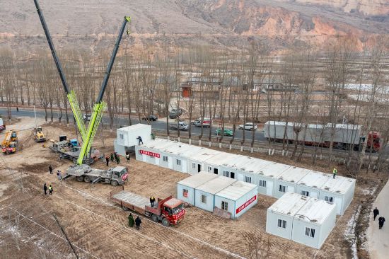 12月22日，在甘肅省臨夏州積石山縣劉集鄉陶家村，施工人員正在吊裝箱式房。人民網記者 翁奇羽攝