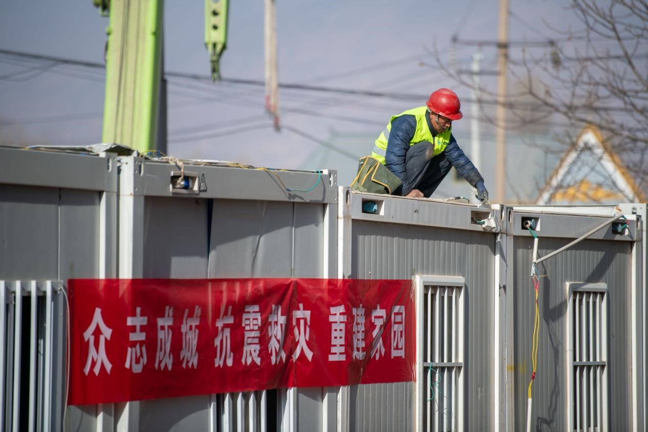 12月22日，在積石山縣劉集鄉陶家村臨時安置箱式房安裝現場，工人正在抓緊施工。人民網記者 翁奇羽攝